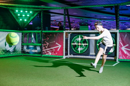 A child taking aim at an interactive target with a football