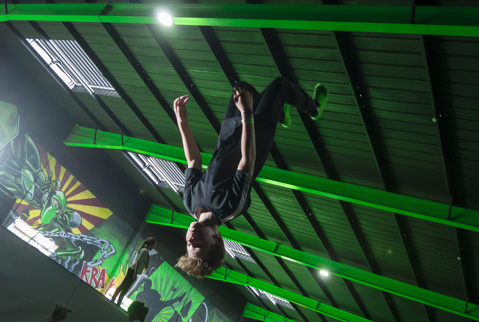Boy upside down mid air with bright light and green style ceiling behind hm.